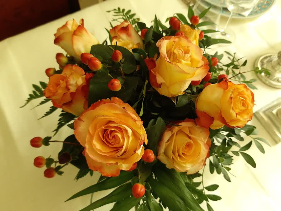 A mixed bouquet of red, pink, and white roses in a clear glass vase.